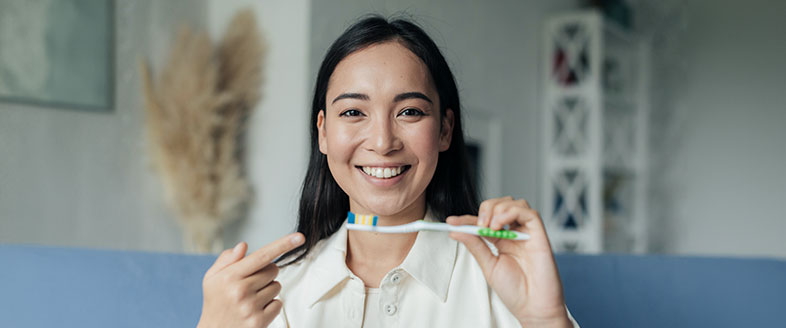 A lady smiling holding a toothbrush