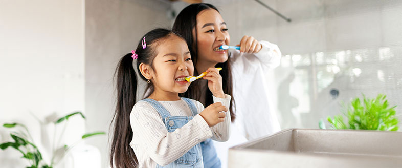 Parent and child brushing teeth together